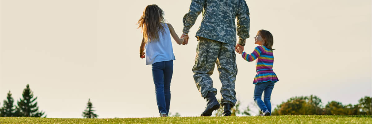 A veteran walks with his daughters.